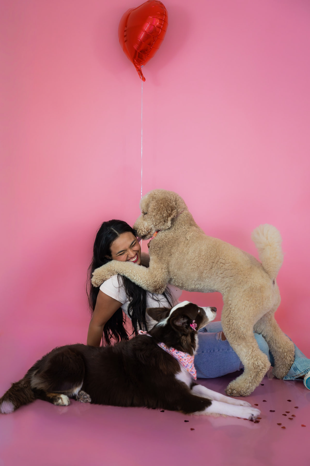 Adaia riendo mientras su caniche la abraza, con dos border collies a su alrededor